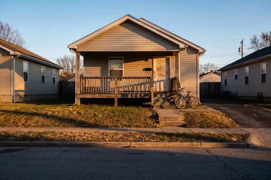 A small starter home with a bicycle by the steps at golden hour